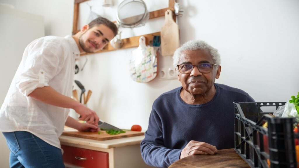 young-man-chopping-vegetable-for-elderly-man