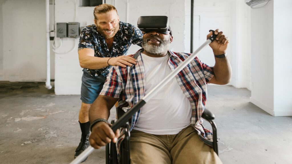 man-on-wheelchair-wearing-VR-lens-being-pushed-by-male-carer
