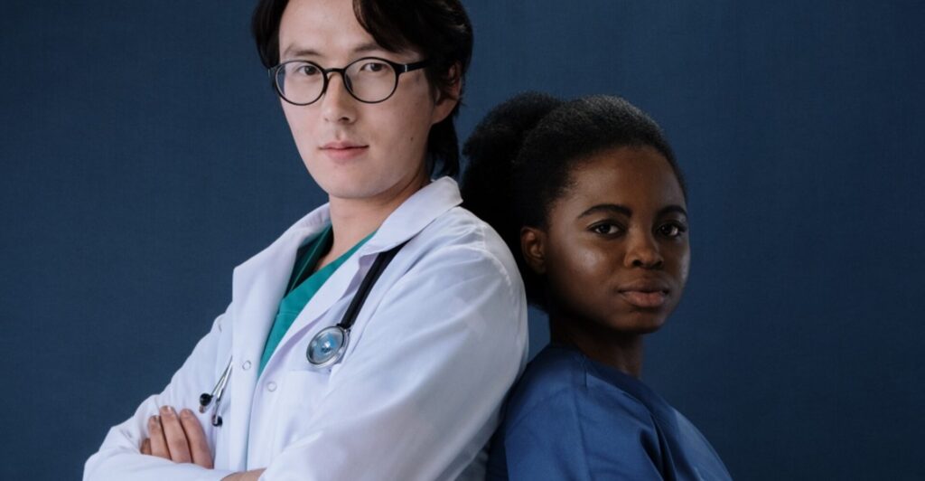man-with-lab-coat-standing-back-to-back-with-lady-wearing-scrubs
